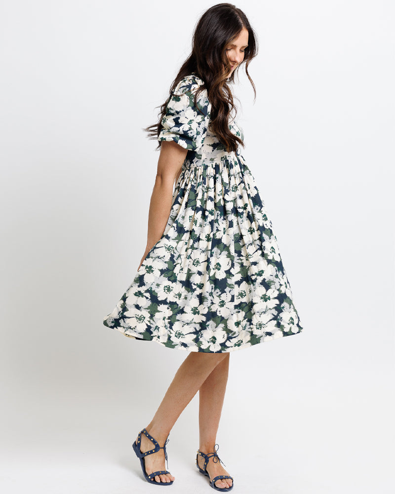 Model wearing a navy, green and white floral print short sleeve square neck knee length dress