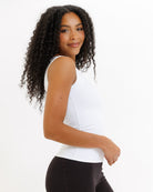 Woman wearing a white tank top and black pants on a white background