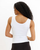 Person wearing a white tank top on a plain background
