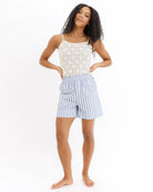 Woman wearing a yellow lace top and blue striped shorts on a white background