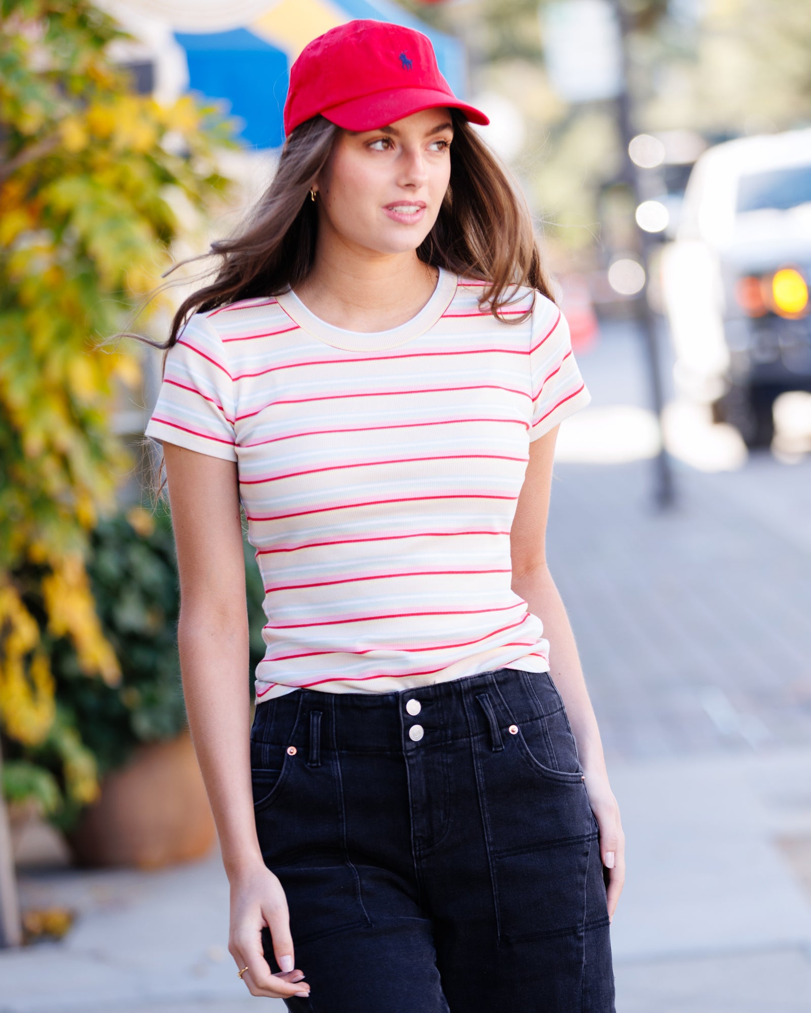 Woman wearing a red cap and striped shirt on a street