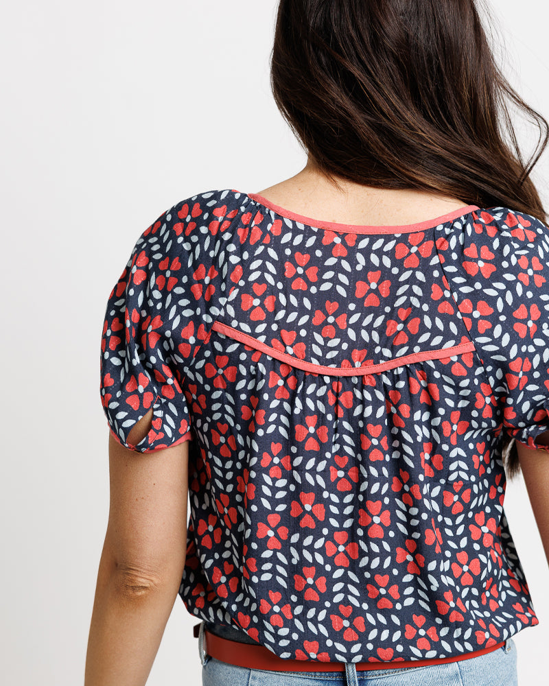 Model wearing a navy blue with orange floral print short sleeve square neck blouse
