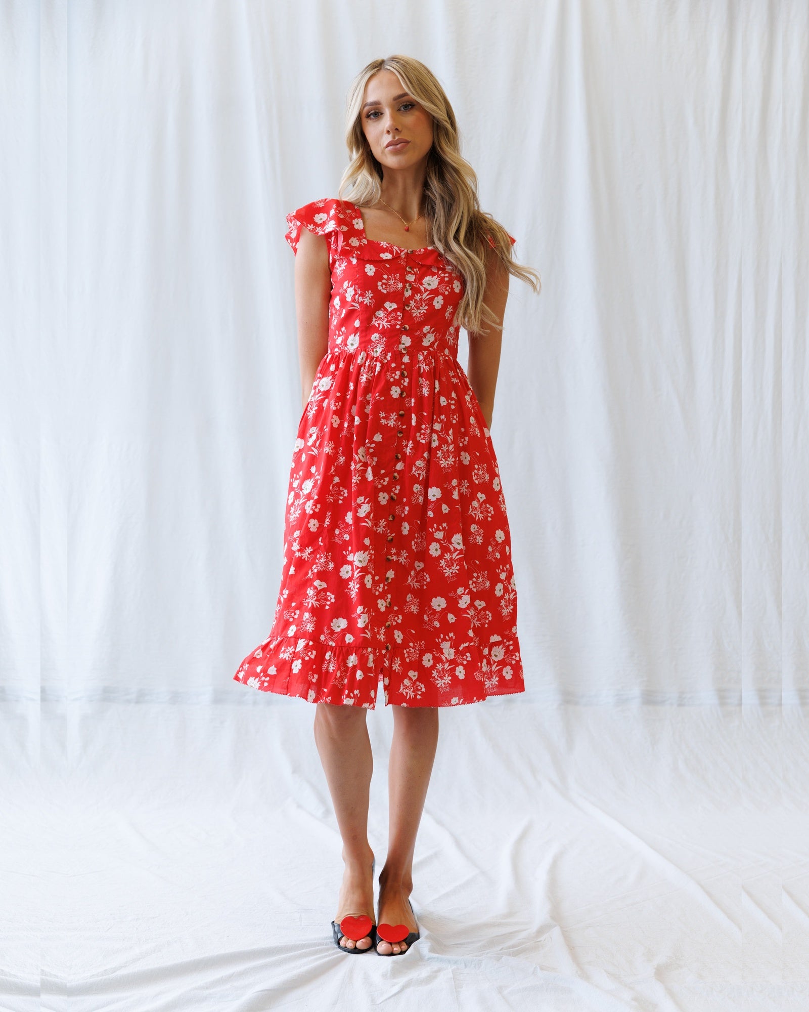 Woman wearing a red floral dress against a white background