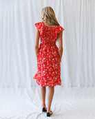 Woman wearing a red floral dress against a white background
