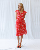 Woman wearing a red floral dress against a white background