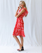 Woman wearing a red floral dress against a white background
