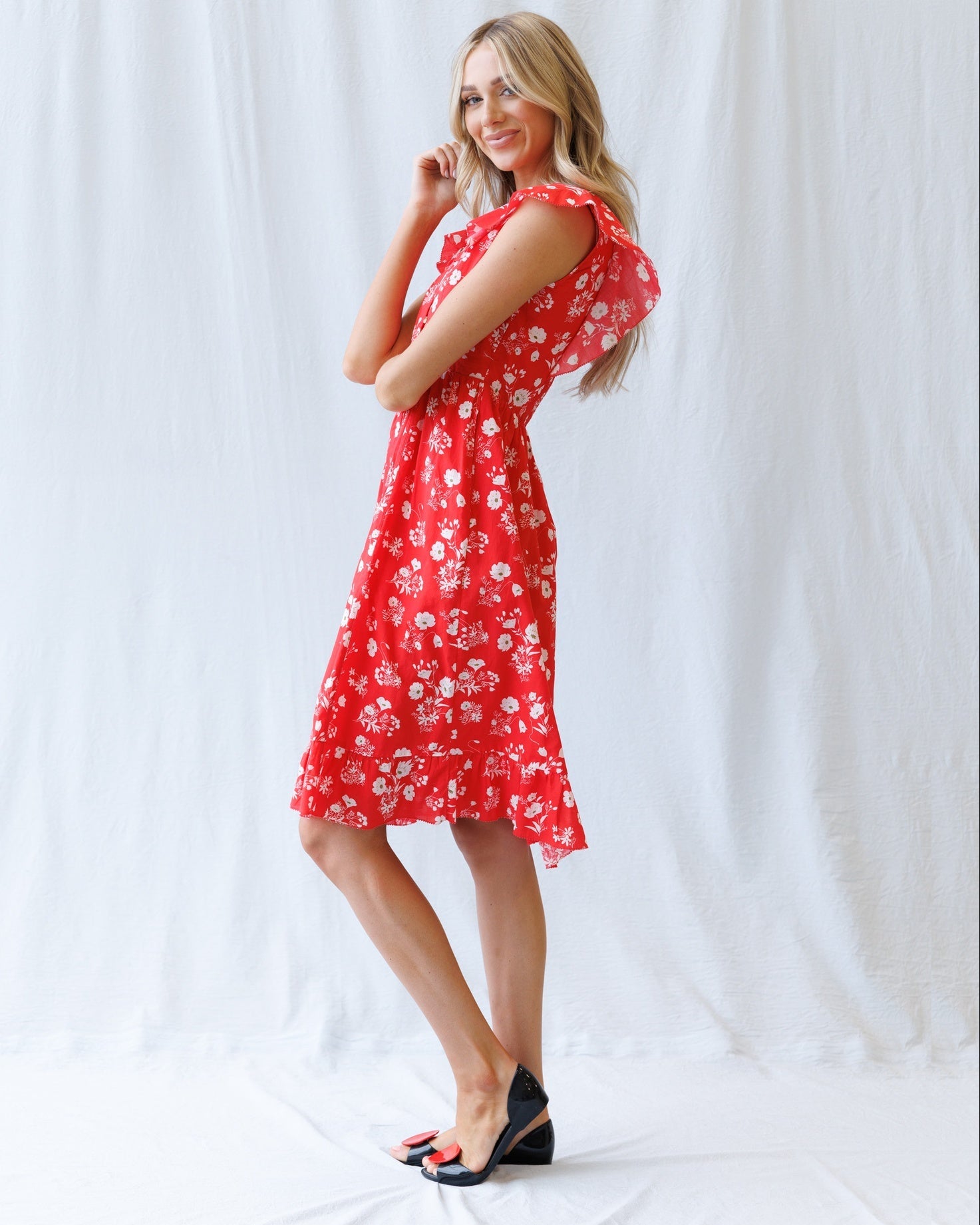 Woman wearing a red floral dress against a white background