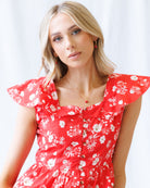 Woman wearing a red floral dress against a white background
