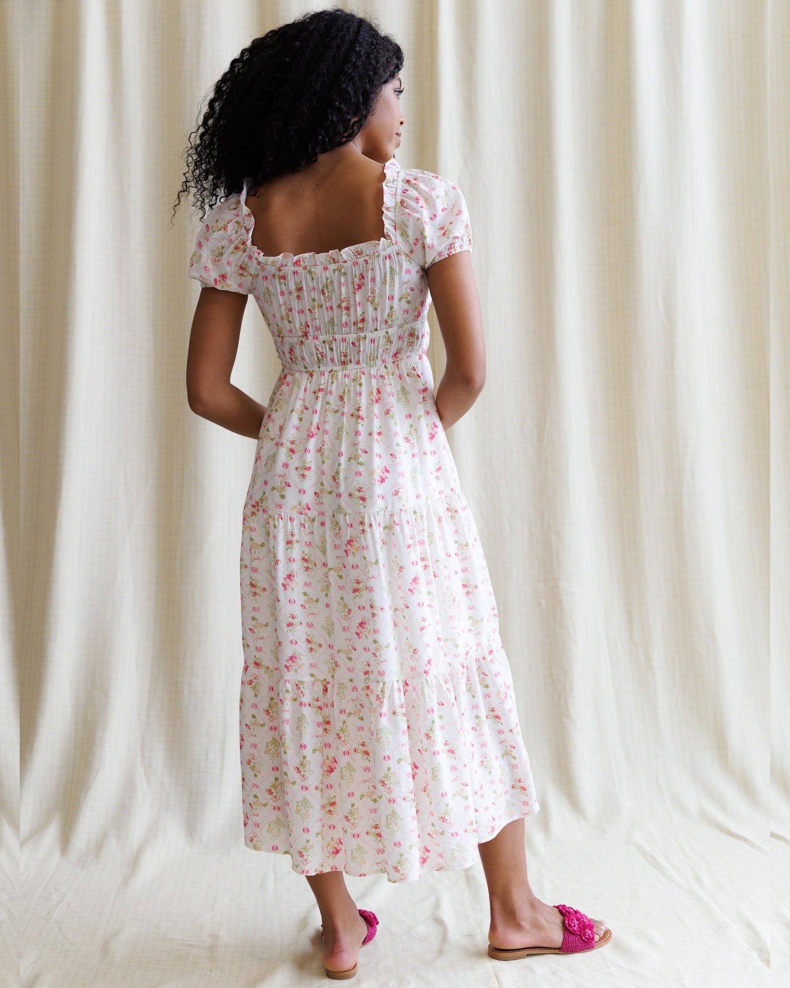 Woman wearing a floral dress against a plain background