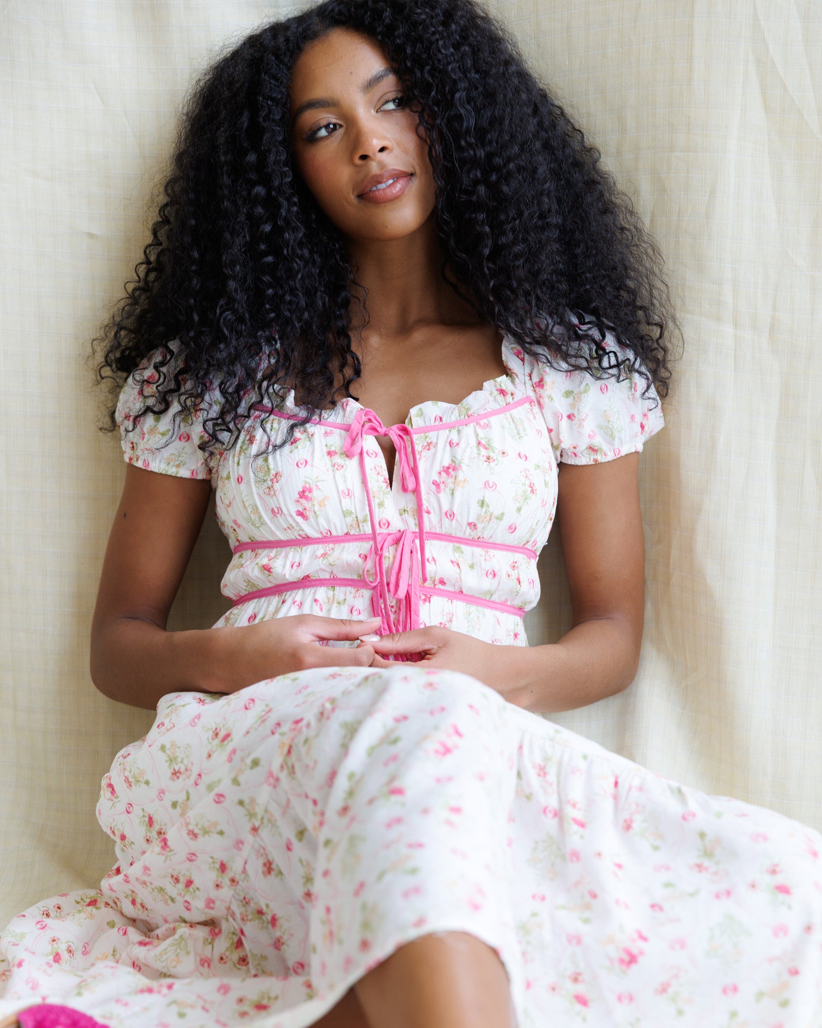 Woman wearing a floral dress with pink accents against a neutral background