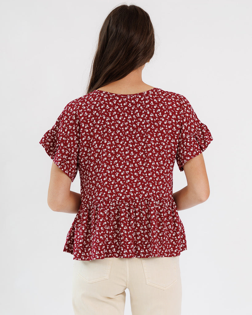 Woman wearing a red floral blouse against a white background