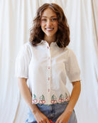 Woman wearing a white shirt with cherry design against a plain background