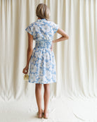 Woman wearing a blue floral dress against a plain background