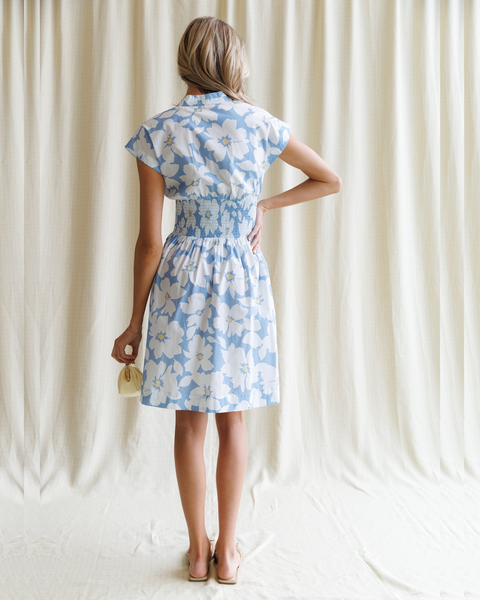 Woman wearing a blue floral dress against a plain background