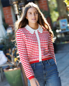Woman wearing a red and white striped sweater with a blurred outdoor background