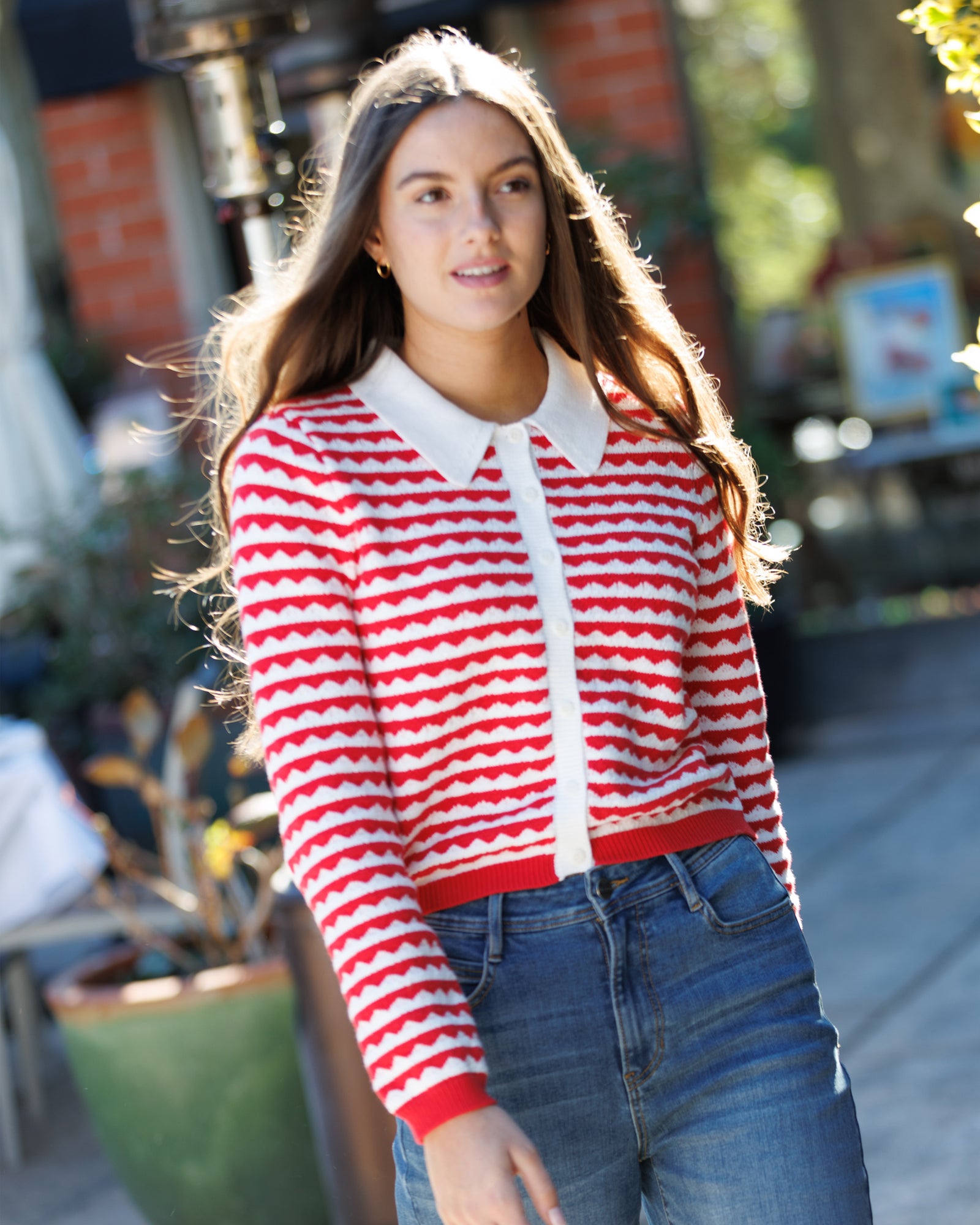 Woman wearing a red and white striped sweater with a blurred outdoor background