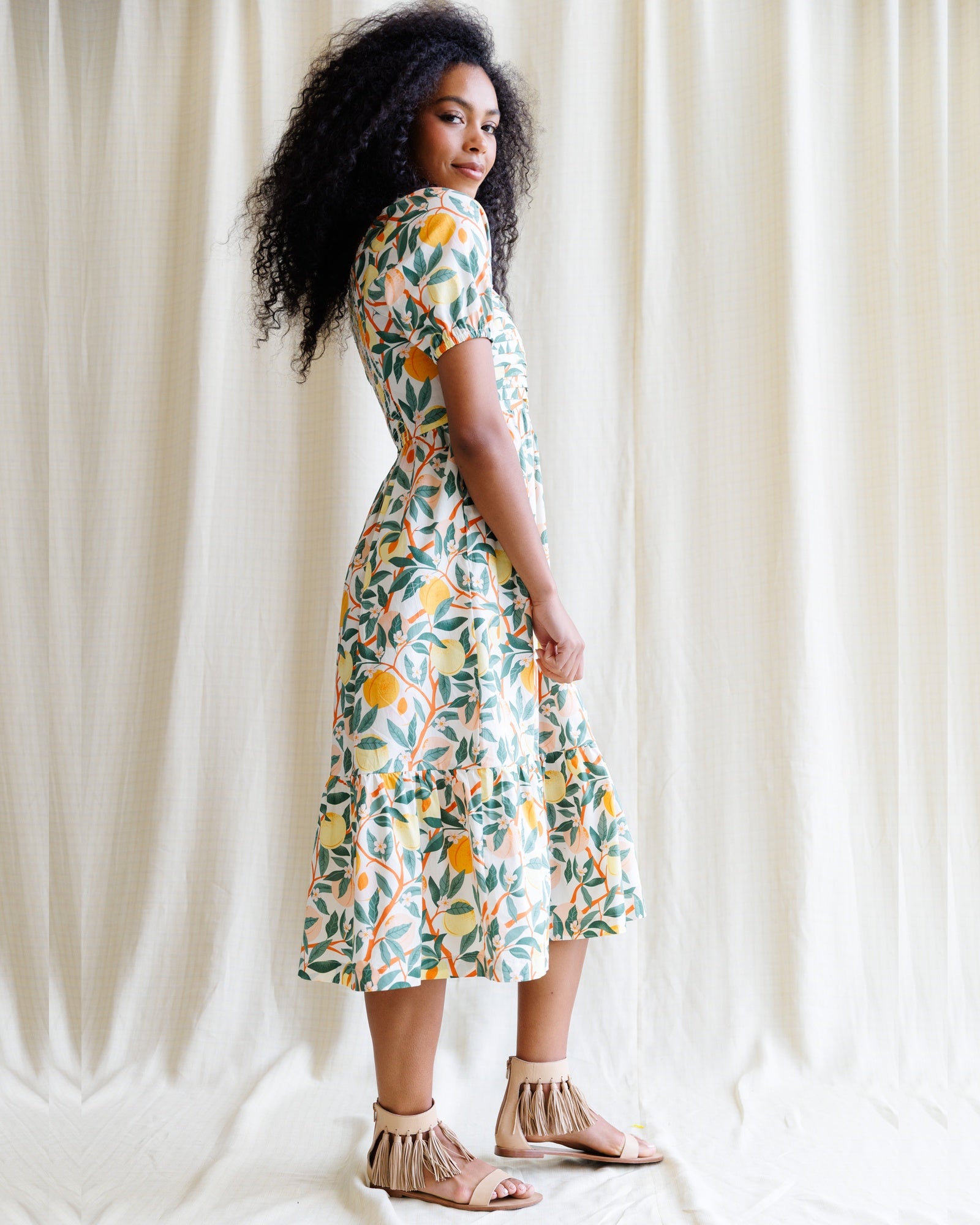 Woman wearing a floral dress standing against a white curtain