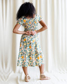 Woman wearing a floral dress against a white curtain background