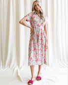 Woman wearing a floral dress standing against a white curtain