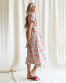 Woman wearing a floral dress standing against a white curtain