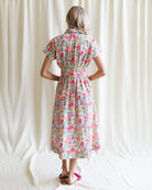 Woman wearing a floral dress against a white curtain background
