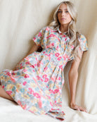 Woman wearing a floral dress sitting on a white couch.