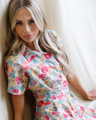 Woman wearing a colorful floral dress against a white background