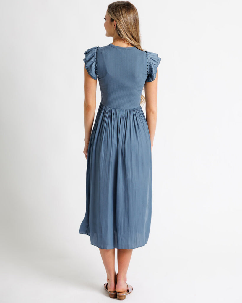 Model wearing a blue short flutter sleeve, crew neck, midi length dress.