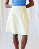 Person wearing a yellow skirt and blue top against a white background