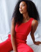 Woman in a red outfit sitting on a white surface