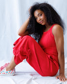Woman in red outfit sitting on a white surface with a light gray background