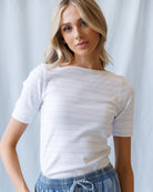Woman wearing a white striped shirt against a light gray background