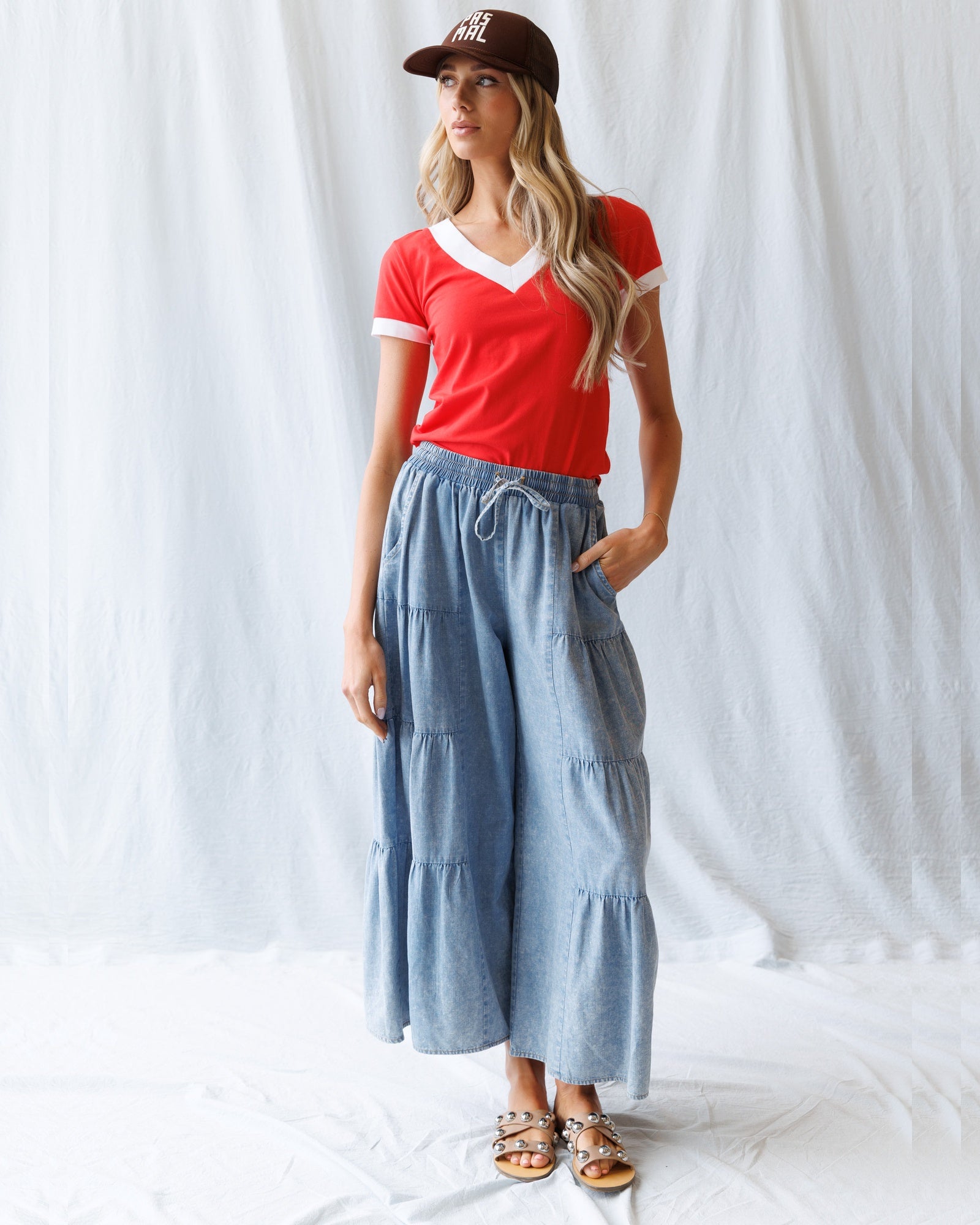 Woman wearing a red top and blue tiered skirt against a white background
