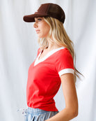 Woman wearing a red shirt and brown cap against a white background