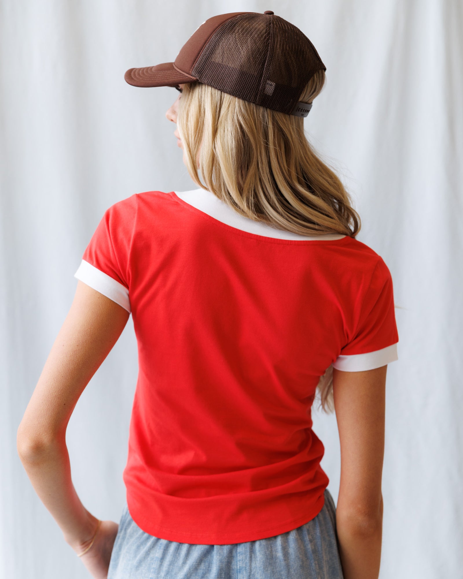 Person wearing a red shirt and brown cap with a white background
