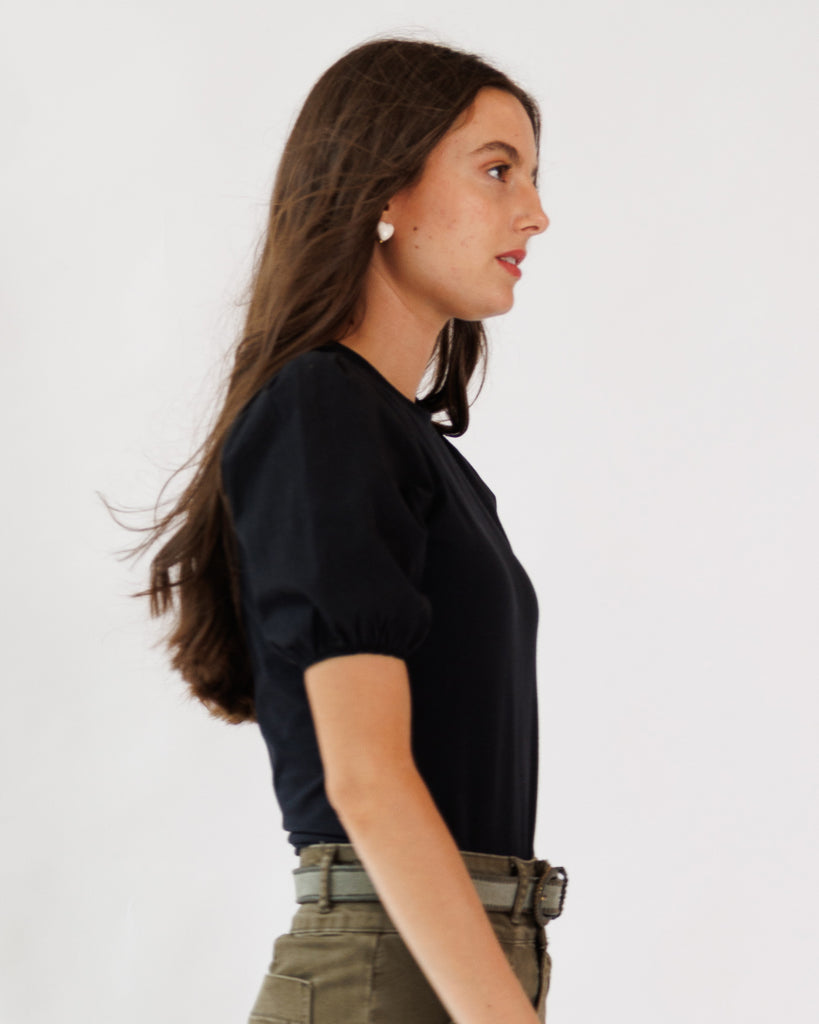 Woman wearing a black top and green pants on a white background