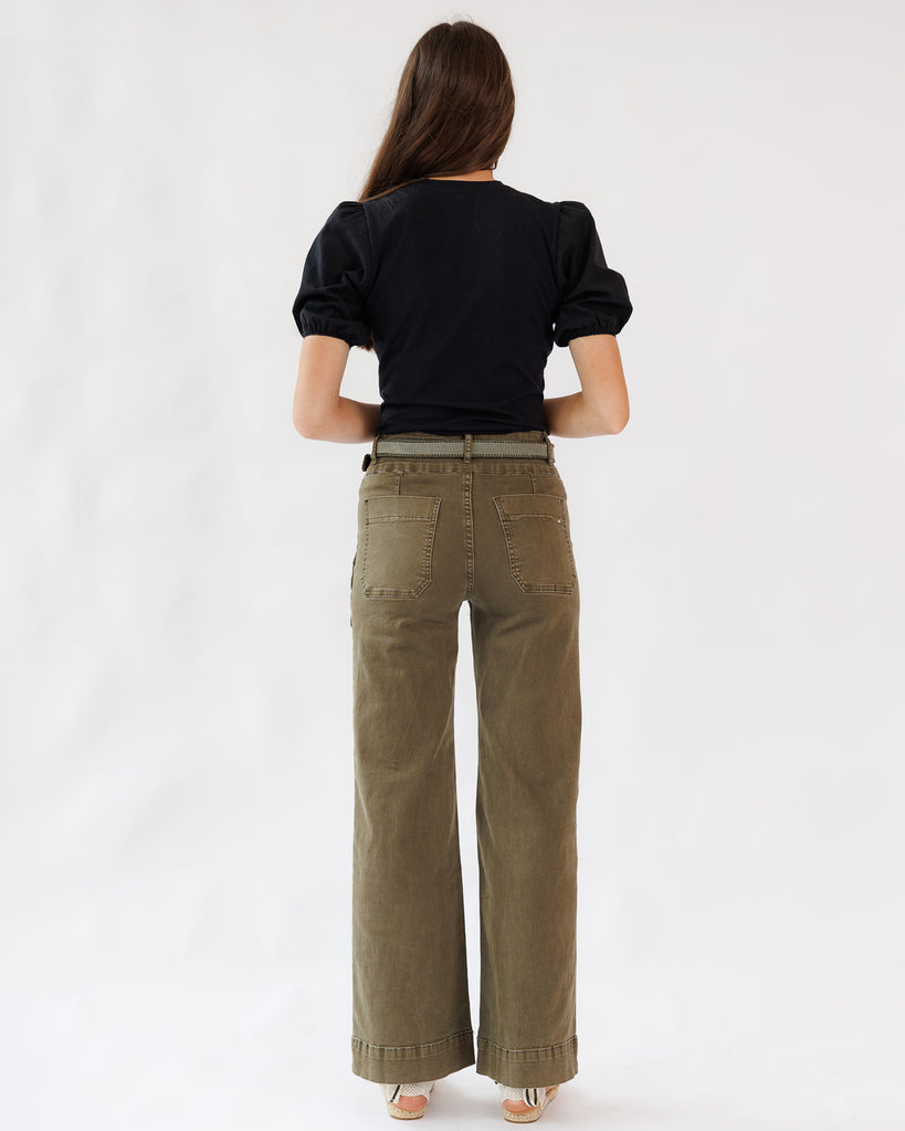 Person wearing a black top and olive green pants on a white background
