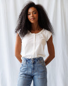 Woman wearing a white blouse and blue jeans against a white background