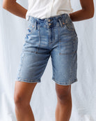 Person wearing light blue denim shorts on a plain background