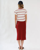 Woman wearing a striped shirt and red skirt on a white background