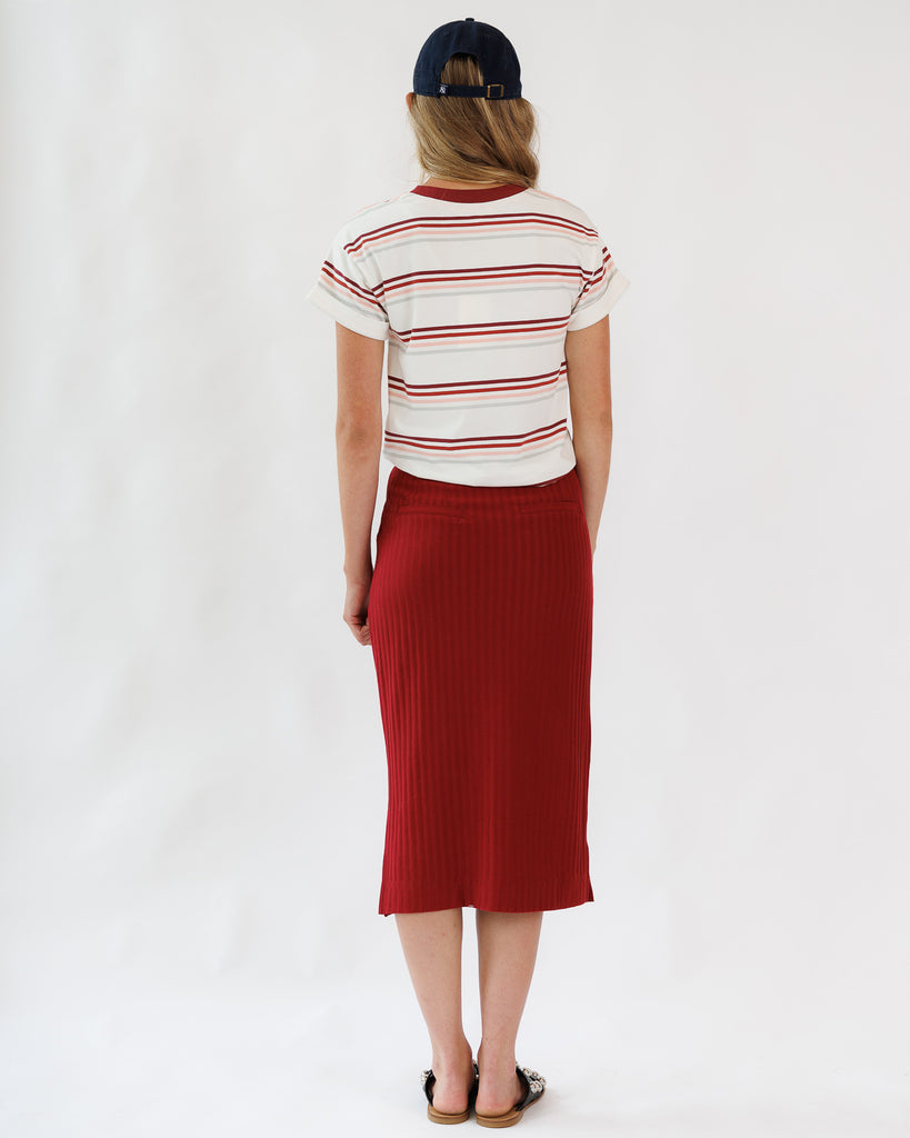 Woman wearing a striped shirt and red skirt on a white background