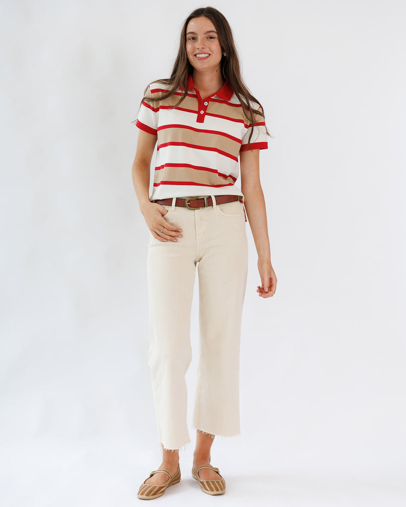 Model wearing a red and tan polo with cream colored cropped jeans.
