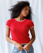 Woman wearing a red textured sweater against a white background