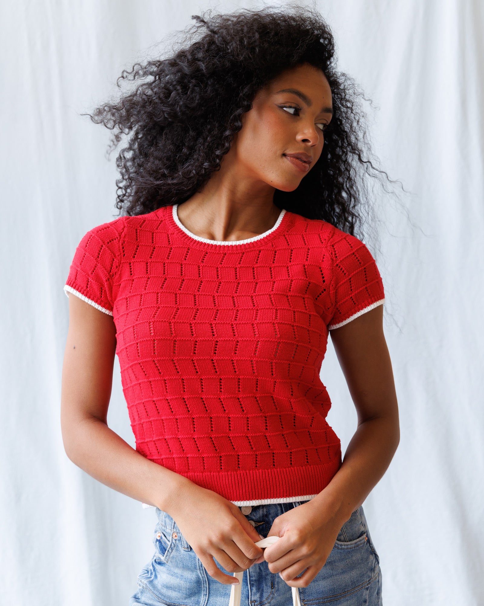 Woman wearing a red textured sweater against a white background