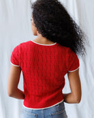 Person wearing a red knitted sweater with a white background