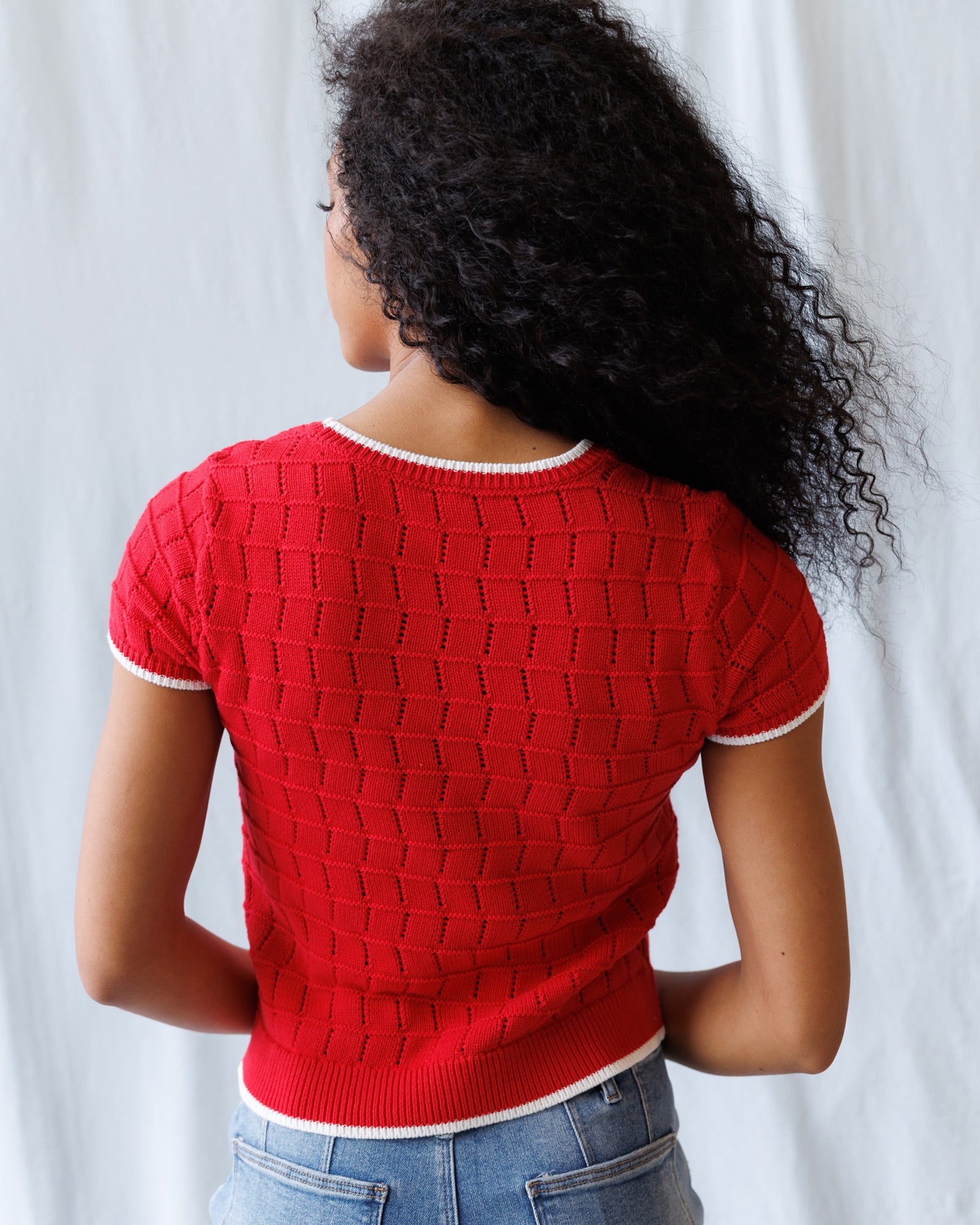 Person wearing a red knitted sweater with a white background