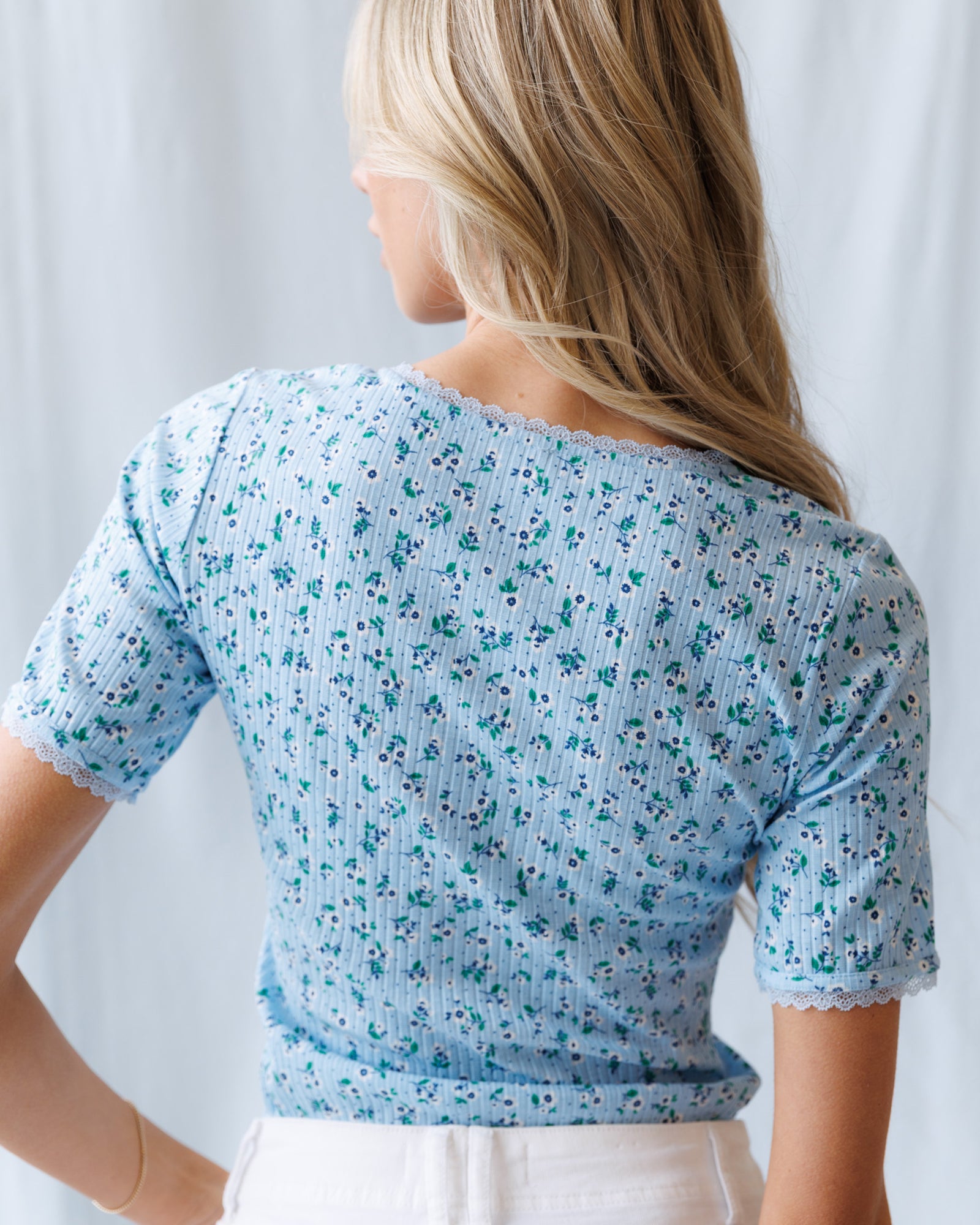 Woman wearing a light blue floral-patterned top against a white background