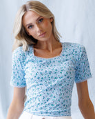 Woman wearing a blue floral top against a white background