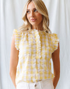 Woman wearing a yellow checkered blouse against a white background