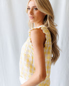 Woman wearing a yellow and white checkered dress against a white background